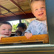 Noah is registered to the contest to win money with this photo: child, boy, smiling, window, wood, train, outdoor, daylight, happy, face, people, family, cap, background, couple, nature, greenery, casual, portrait, candid