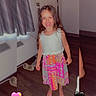 child, girl, smiling, barefoot, colorful_dress, indoor, wooden_floor, curtain, door, heart_emoji, reflection, happy, long_hair, patterned_clothing, room, playful, young, standing, barefoot_child, casual