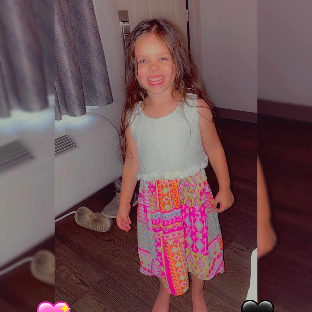Harper is registered to the contest to win money with this photo: child, girl, smiling, barefoot, colorful_dress, indoor, wooden_floor, curtain, door, heart_emoji, reflection, happy, long_hair, patterned_clothing, room, playful, young, standing, barefoot_child, casual