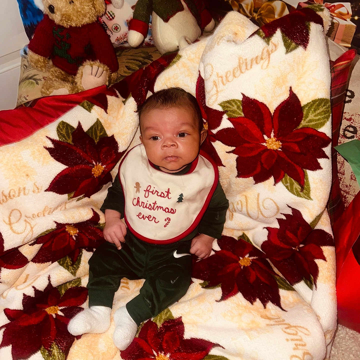 Kasai is registered to the contest to win money with this photo: baby, bib, blanket, christmas, clothing, cute, decoration, festive, green, holiday, indoors, infant, plush_toy, poinsettia, portrait, red, sitting, snowman, teddy_bear, white