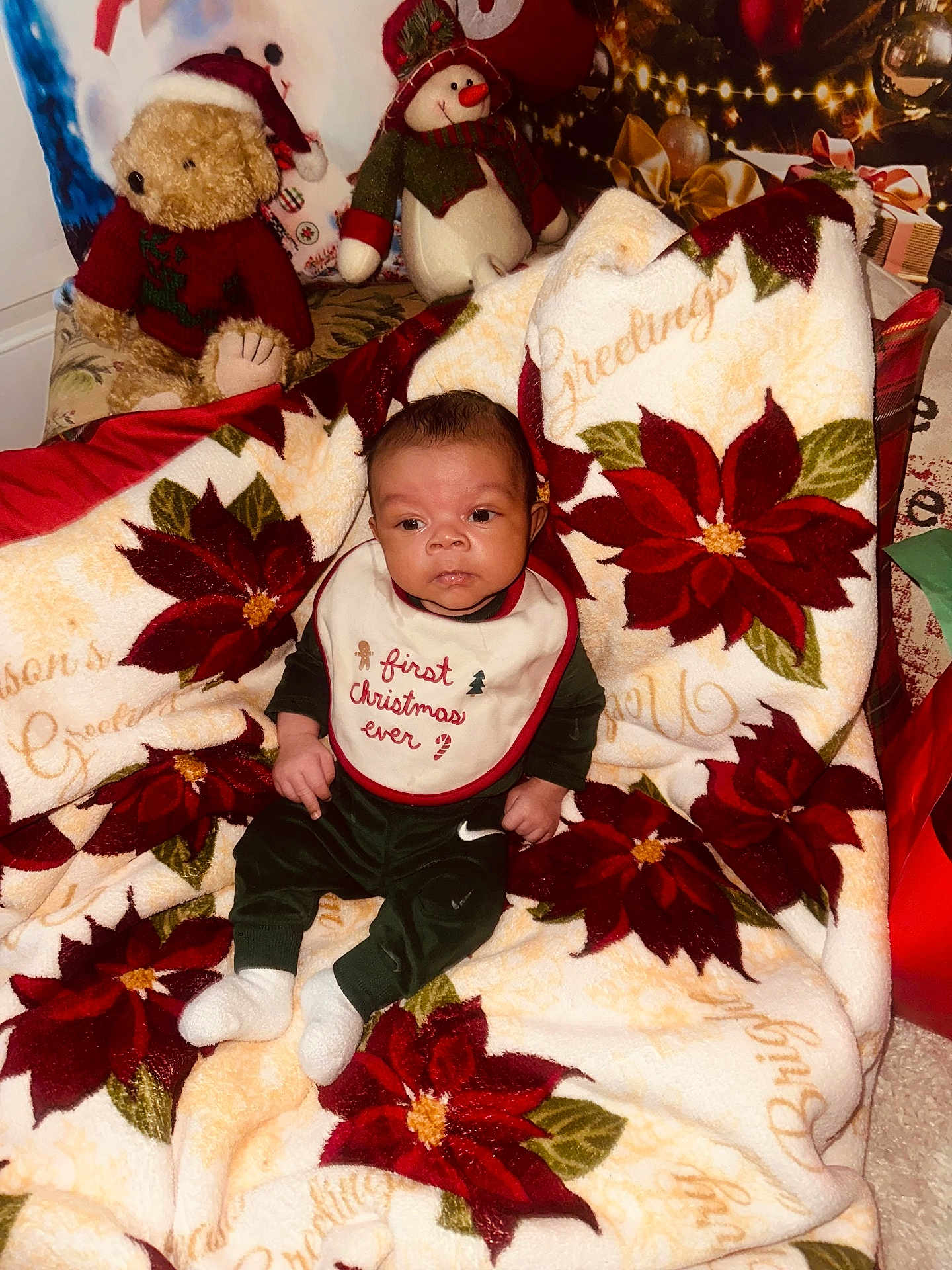 Kasai is registered to the contest to win money with this photo: baby, infant, blanket, christmas, holiday, poinsettia, plush_toy, teddy_bear, snowman, bib, clothing, sitting, indoors, festive, decoration, red, green, white, cute, portrait