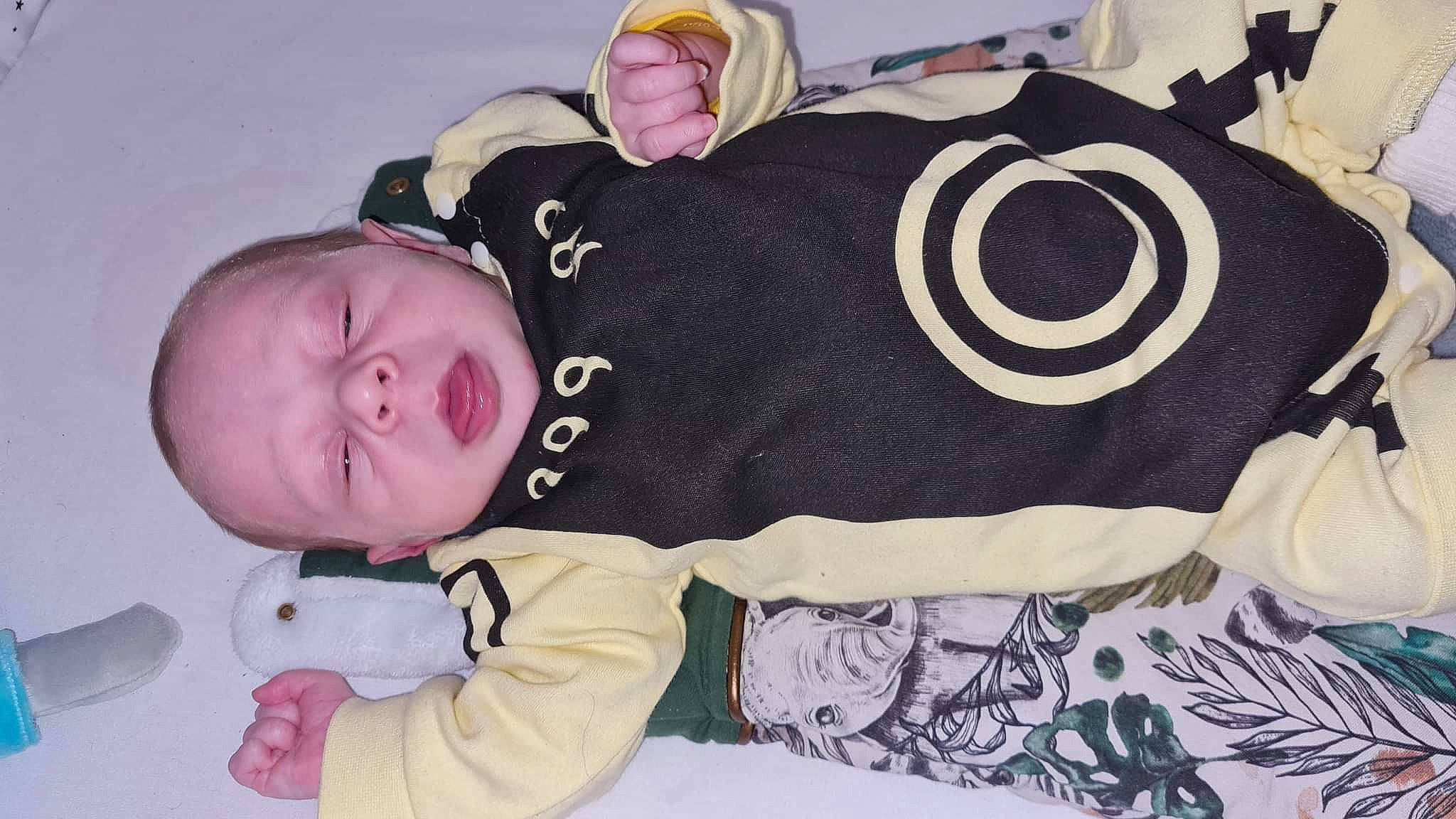 Allan participe au concours pour gagner de l'argent avec cette photo : baby, baby_products, baby_toddler_clothing, bedding, cheek, child, comfort, fashion_accessory, happy, linens, pattern, person, pink, skin, sleeve, smile, textile, toddler, white