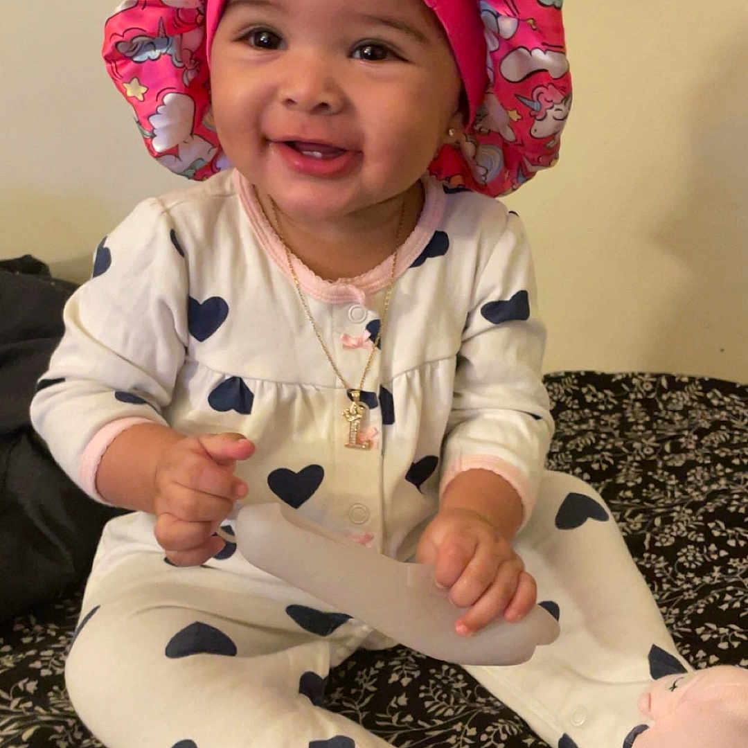 Lailahni is registered to the contest to win money with this photo: accessories, baby, bonnet, cap, clothing, coat, costume, face, happy, hat, head, jewelry, necklace, pajamas, pants, person, photography, portrait, sitting, smile