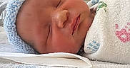 Osana is registered to the contest to win money with this photo: newborn, baby, sleeping, hospital, bassinet, knit_hat, blue_hat, blanket, swaddled, portrait, face, closed_eyes, peaceful, infant, resting, bedding, medical_setting, close_up, cozy, photography