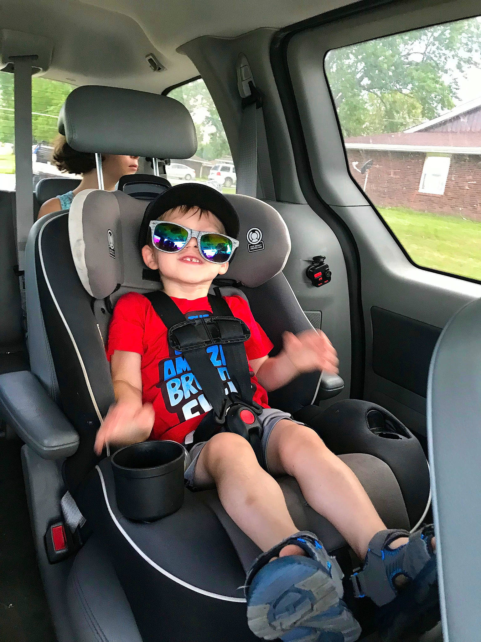 Jaxson is registered to the contest to win money with this photo: auto_part, automotive_design, automotive_exterior, car, car_seat, car_seat_cover, head_restraint, mode_of_transport, motor_vehicle, person, personal_luxury_car, seat_belt, shorts, steering_part, steering_wheel, sunglasses, toddler, vehicle, vehicle_door, white