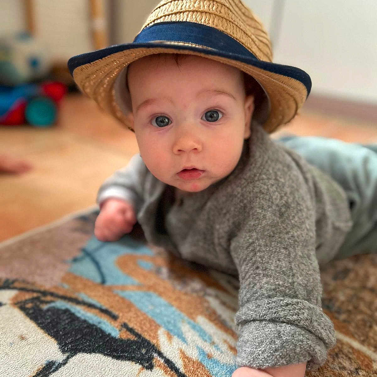 Julian a rejoint le concours — aidez-le/la à gagner de superbes lots ! baby, child, cozy, crawling, curious, cute, expression, face, floor, gray_sweater, hand, hat, indoor, infant, patterned_rug, portrait, rug, soft_focus, straw_hat, wide_eyes