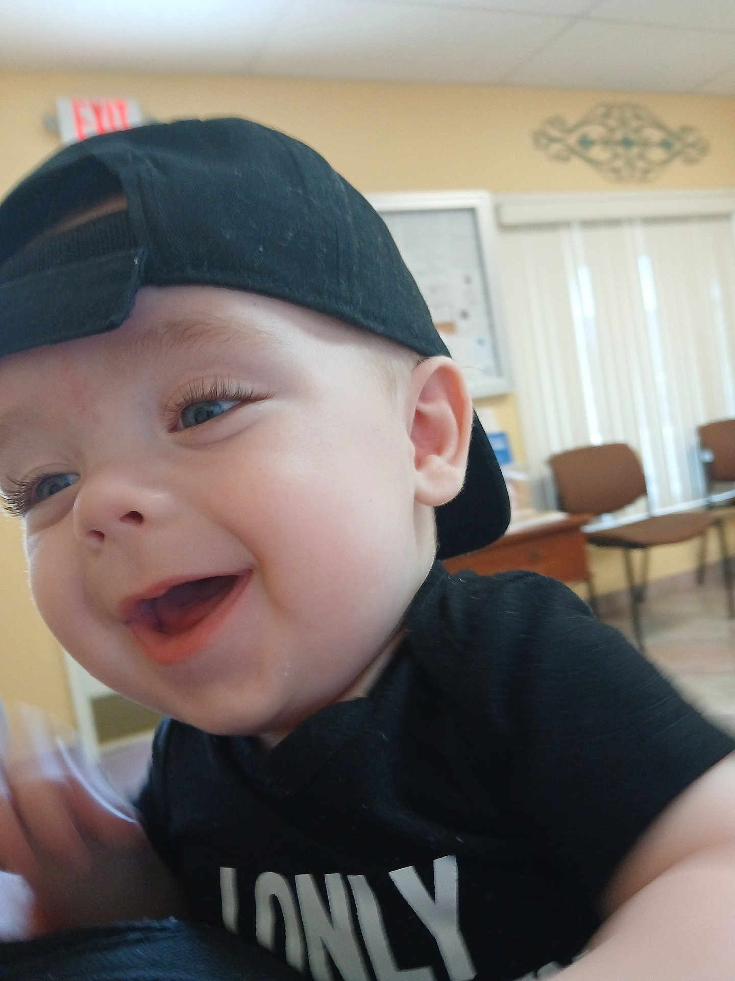 Ryder joined the competition — help win amazing prizes! baby, child, smiling, black_cap, black_shirt, indoor, face, happy, young_child, person, candid, cute, expression, headwear, seated, furniture, blurred_background, room, joyful, portrait