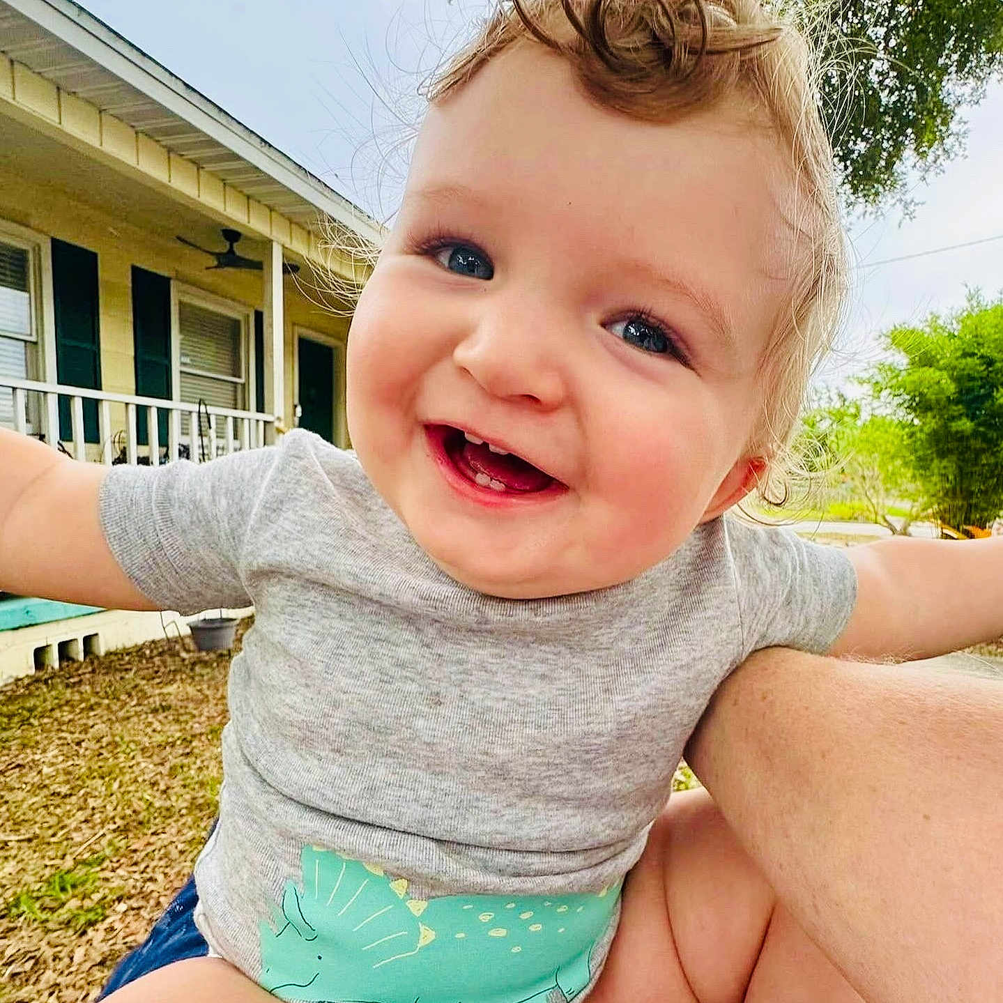 Eros joined the competition — help win amazing prizes! arms_outstretched, baby, child, closeup, curly_hair, cute, daylight, diaper, dinosaur_print, face, grass, grey_shirt, happy, house, outdoor, person, portrait, smiling, tree, yard