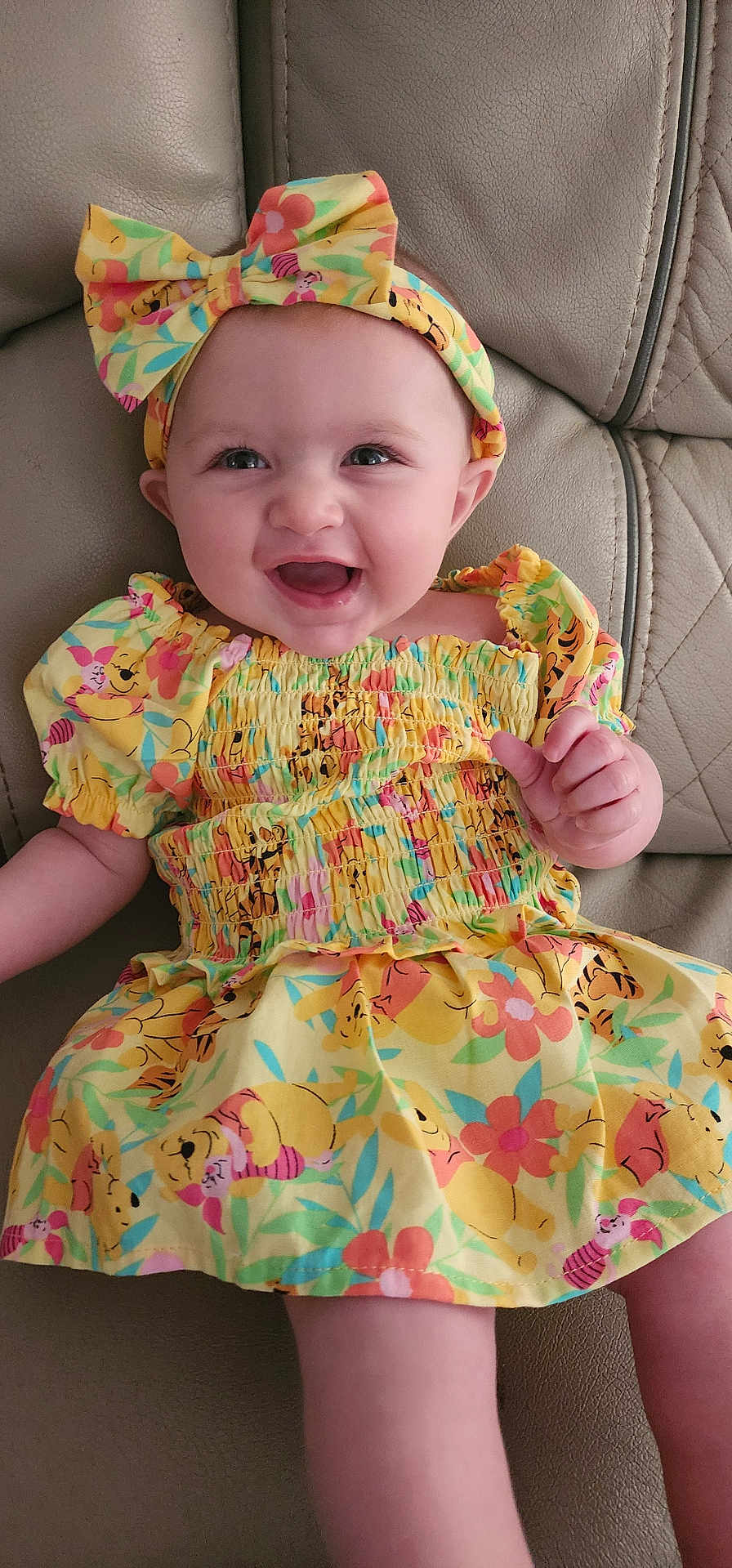 Charlotte joined the competition — help win amazing prizes! baby, child, smiling, dress, headband, yellow, cartoon_print, sitting, couch, leather, happy, portrait, indoor, cute, infant, person, clothing, colorful, face, young