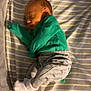 baby, bed, child, cozy, crib, cute, green_clothing, grey_pants, indoors, infant, mesh, newborn, peaceful, portrait, resting, sleeping, socks, soft_lighting, stars, striped_bedding