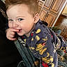 toddler, child, pajamas, mickey_mouse, smile, finger_in_mouth, blanket, indoor, wooden_cabinets, cozy, playful, cute, face, blue_eyes, hair, furniture, home, person, portrait, young_child