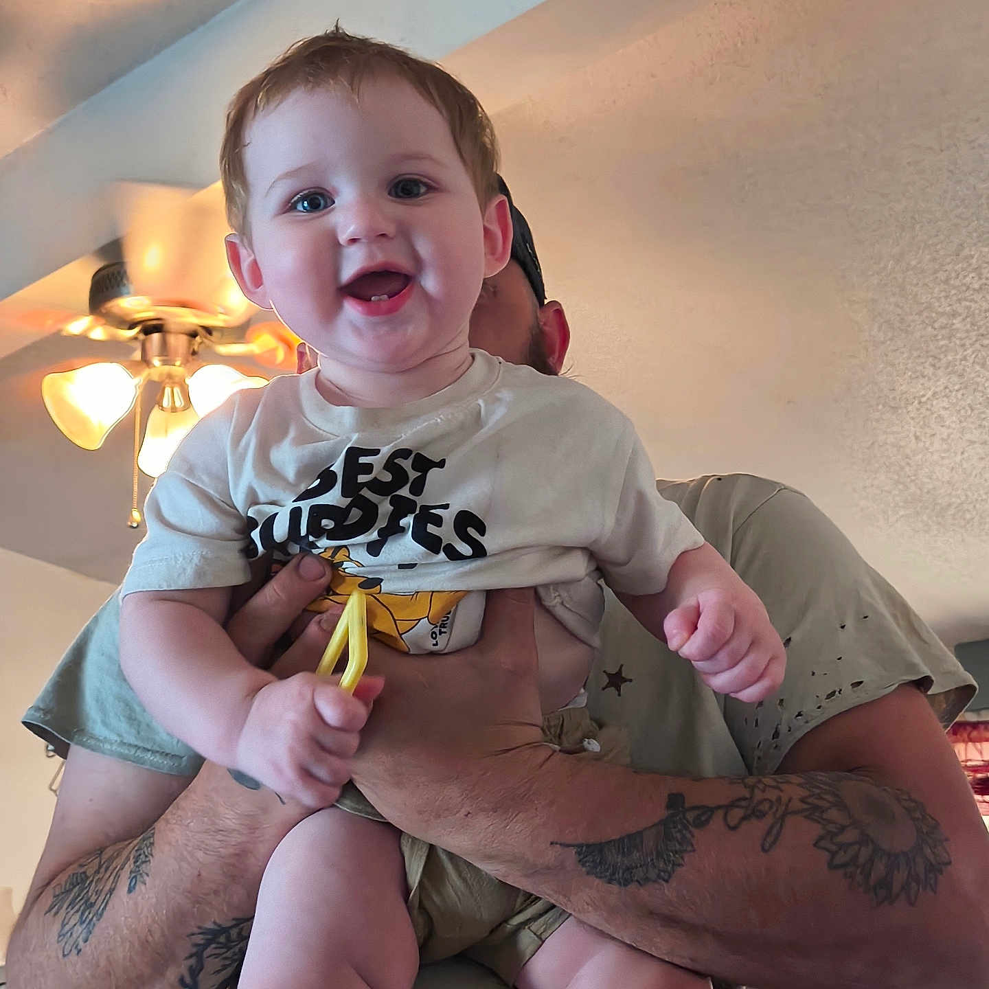 Oaklee joined the competition — help win amazing prizes! baby, child, smiling, happy, person, tattoo, arm, indoor, ceiling_fan, light, tshirt, holding, adult, face, hands, home, decor, cute, joy, portrait