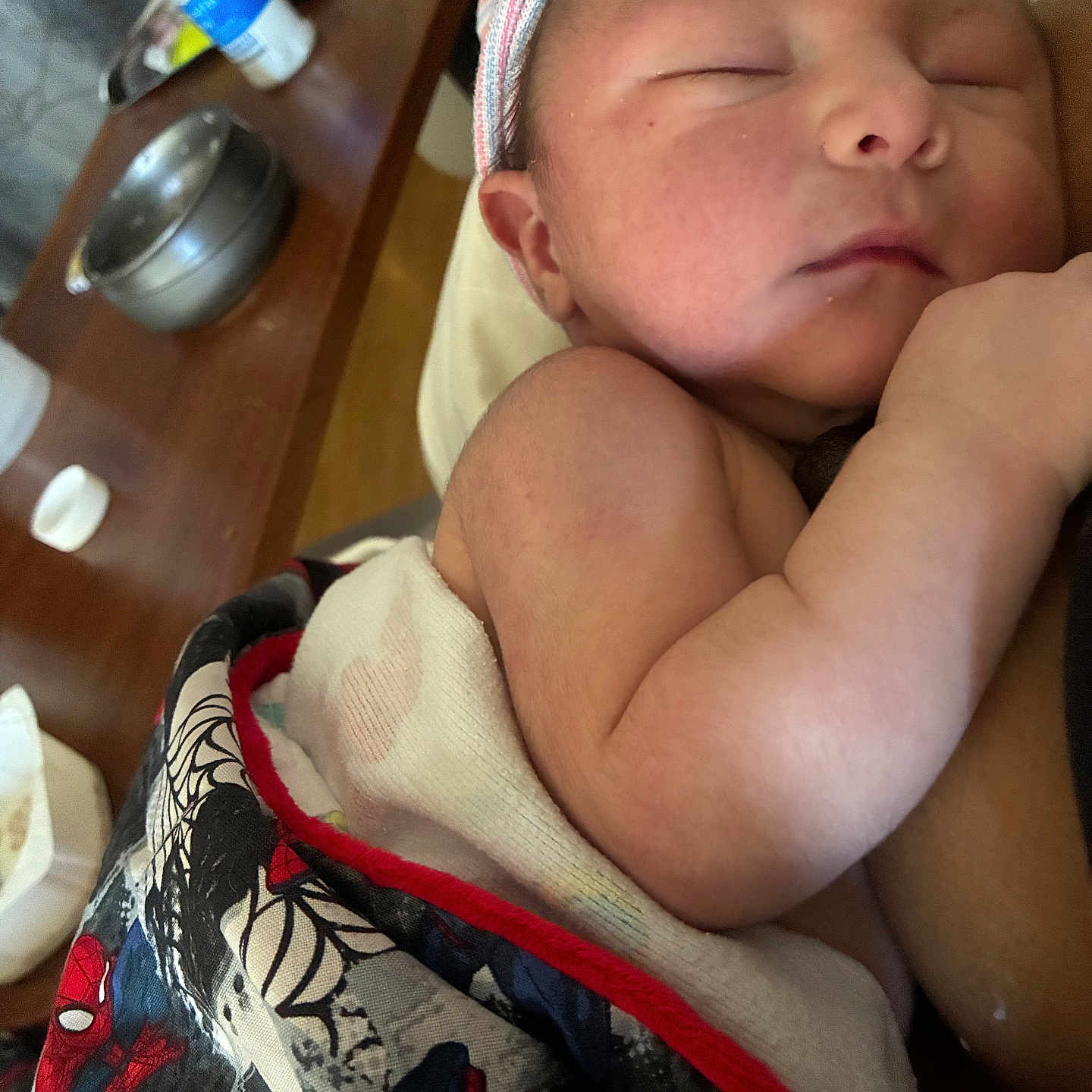 Hay Maddox joined the competition — help win amazing prizes! newborn, baby, sleeping, blanket, spiderman, hat, arm, skin, person, indoors, wooden_table, bottle, bowl, fabric, closeup, peaceful, child, infant, wrapped, resting