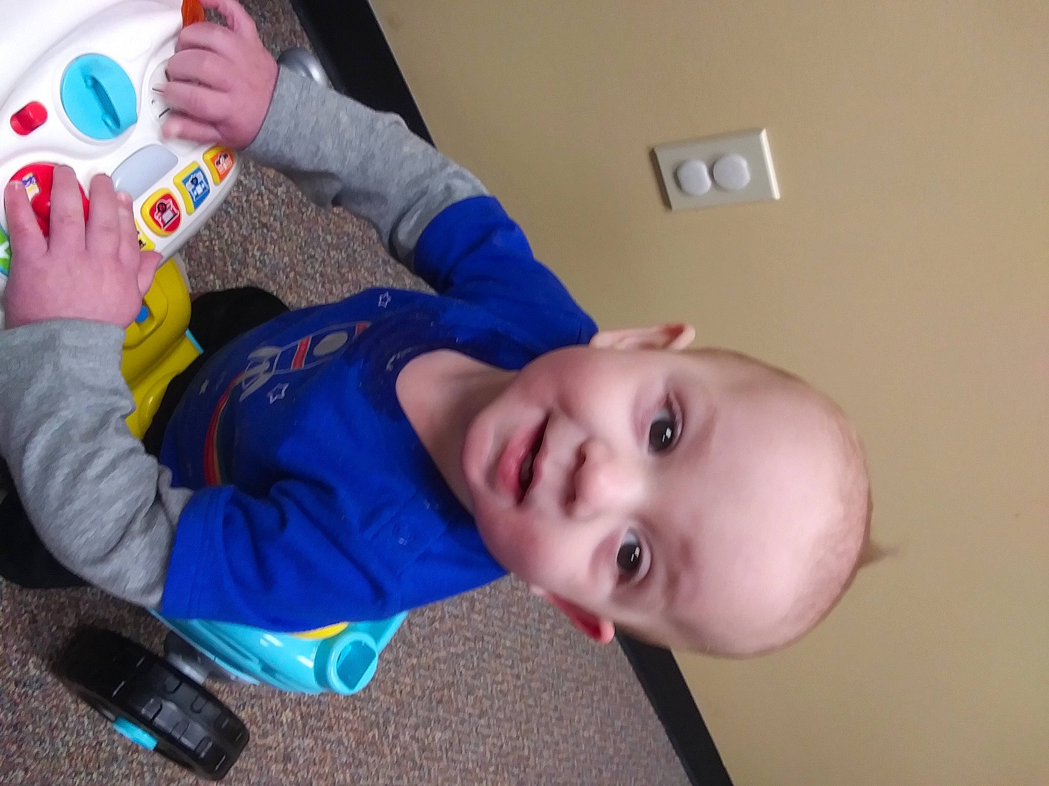 Aiden is registered to the contest to win money with this photo: baby, baby_products, baby_toddler_clothing, baby_toys, cheek, child, drinkware, electric_blue, flooring, fun, gadget, happy, mobile_phone, nose, person, play, room, sitting, skin, smile