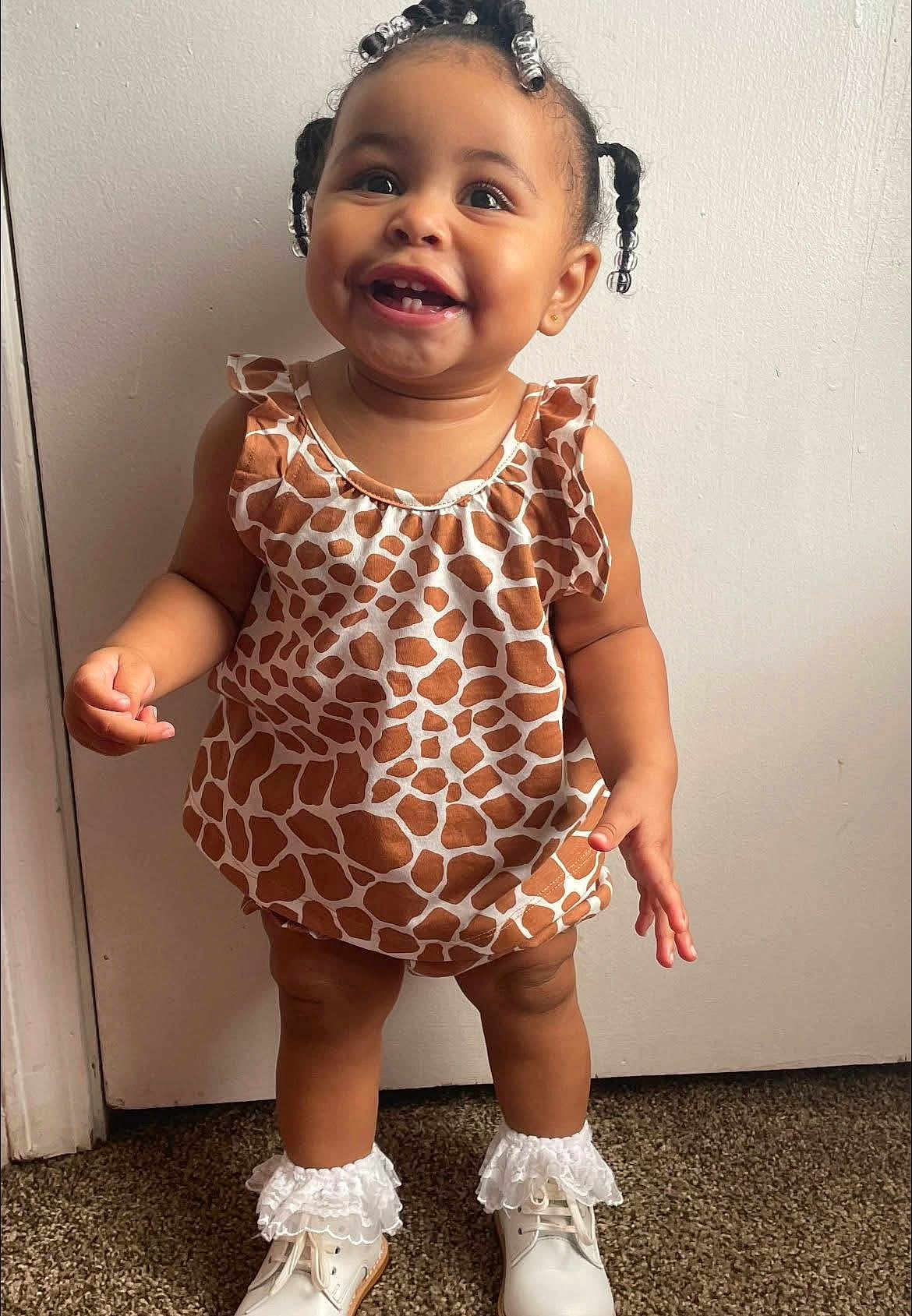Trú is registered to the contest to win money with this photo: toddler, child, smiling, standing, giraffe_pattern, dress, white_shoes, frilly_socks, indoor, carpet, cute, happy, person, face, young_child, baby, hair_beads, portrait, clothing, footwear