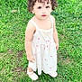 toddler, child, curly_hair, white_dress, white_shoes, grass, outdoor, greenery, cute, portrait, young_child, standing, nature, daylight, curious, innocent, person, small_child, summer, playful