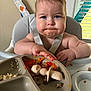 baby, high_chair, food, messy, plate, silicone_pacifier, indoor, window, blinds, expression, cheeks, arm, hand, skin, hair, child, meal, tongue, table, light