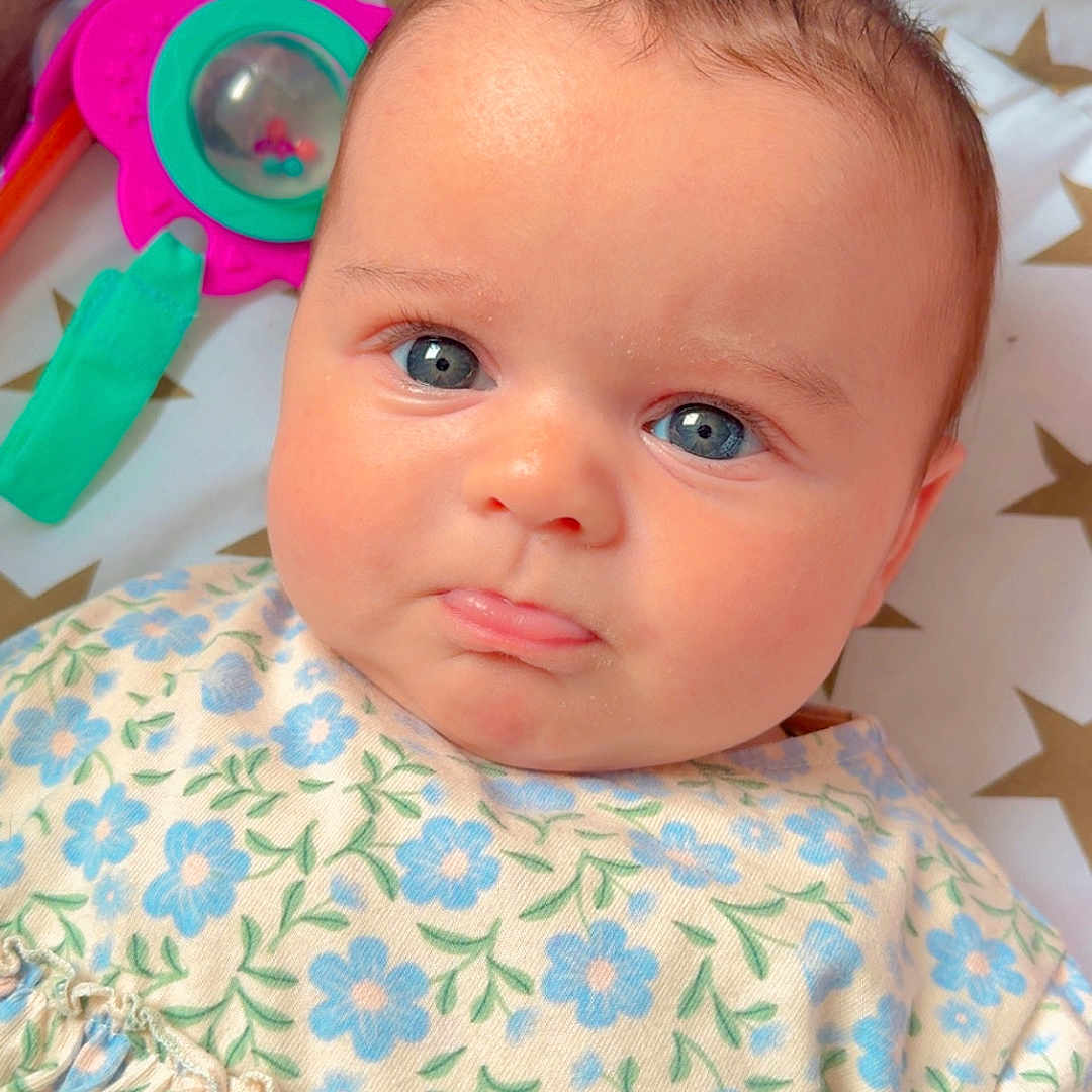 Malya a rejoint le concours — aidez-le/la à gagner de superbes lots ! baby, child, blue_eyes, floral_dress, face, tongue, toy, colorful, star_pattern, bedding, cute, infant, portrait, expression, indoors, soft_lighting, skin, person, closeup, adorable