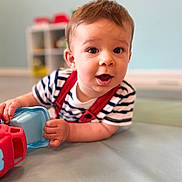 Hugo participe au concours pour gagner de l'argent avec cette photo : baby, child, toy, striped_shirt, indoor, playroom, floor_mat, curious, happy, infant, person, face, hand, crawling, cute, young, expression, soft_light, blurred_background, red_suspender