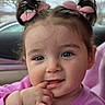Stella is registered to the contest to win money with this photo: toddler, child, baby, face, hair_bows, pink_sweater, finger_in_mouth, cute, portrait, closeup, indoors, car_interior, expression, young_child, skin, eyelashes, cheeks, smile, curly_hair, playful