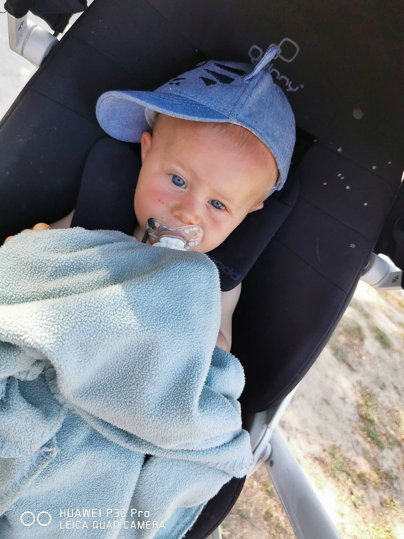 Nateo a rejoint le concours — aidez-le/la à gagner de superbes lots ! auto_part, baby, baby_carriage, baby_products, baby_toddler_clothing, car_seat, child, comfort, electric_blue, family_car, fashion_accessory, grass, hat, luxury_vehicle, outerwear, person, sitting, sun_hat, toddler, tree