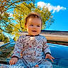 baby, child, pajamas, car, hood, outdoor, sky, trees, sunlight, smile, happy, nature, portrait, infant, clothing, blue_sky, greenery, time_stamp, sitting, cute