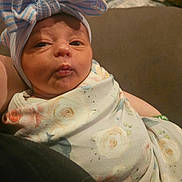 Melesia is registered to the contest to win money with this photo: baby, newborn, infant, blanket, floral_pattern, hat, bow, headwear, face, swaddled, indoor, person, cute, expression, skin, closeup, portrait, cozy, soft, wrapped