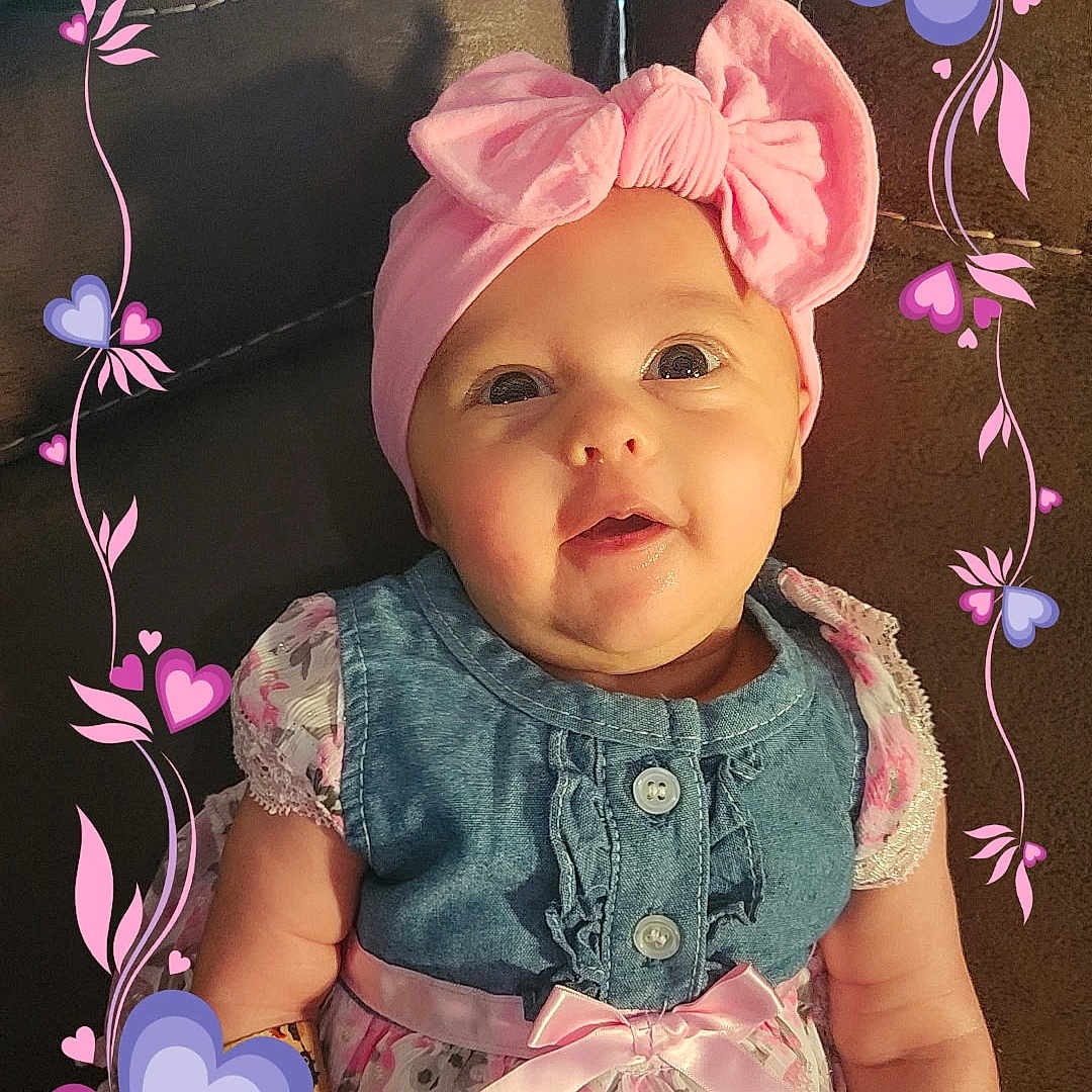 Melesia joined the competition — help win amazing prizes! baby, child, pink_bow, headband, floral_dress, denim_top, couch, smiling, cute, portrait, infant, sitting, indoors, heart_frame, decorative_frame, happy, young_child, pink, purple, clothing