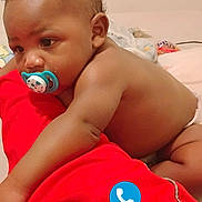 Zadyn joined the competition — help win amazing prizes! baby, pacifier, red_fabric, curly_hair, diaper, indoor, bed, infant, child, skin, face, arm, hand, expression, phone_icons, digital_overlay, background, blanket, candid, portrait