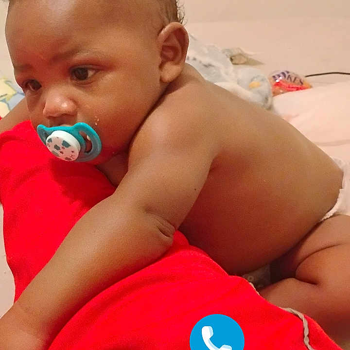 Zadyn joined the competition — help win amazing prizes! baby, pacifier, red_fabric, curly_hair, diaper, indoor, bed, infant, child, skin, face, arm, hand, expression, phone_icons, digital_overlay, background, blanket, candid, portrait