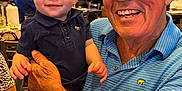 Joseph joined the competition — help win amazing prizes! baby, elderly_man, restaurant, smile, joy, holding, child, people, indoor, casual_clothing, table, chair, background, television, happy, face, skin, person, adult, toddler