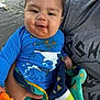 baby, blue_shirt, casual_clothing, child, cute, dirty_face, hand, holding, infant, messy_face, nature, outdoor, person, portrait, rocks, smiling, snack, towel, water, young_child