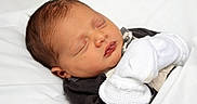 Clayton is registered to the contest to win money with this photo: baby, bed, blanket, bodypart, clothing, face, finger, furniture, glove, hand, head, newborn, person, photography, portrait, sleeping