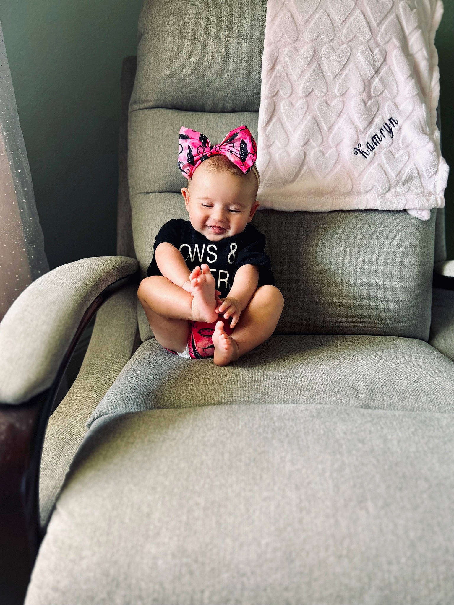 Kamryn is registered to the contest to win money with this photo: baby, baby_toddler_clothing, comfort, couch, dress, eye, head, human_body, human_leg, joy, knee, leg, linens, person, room, sitting, sleeve, smile, t_shirt, thigh