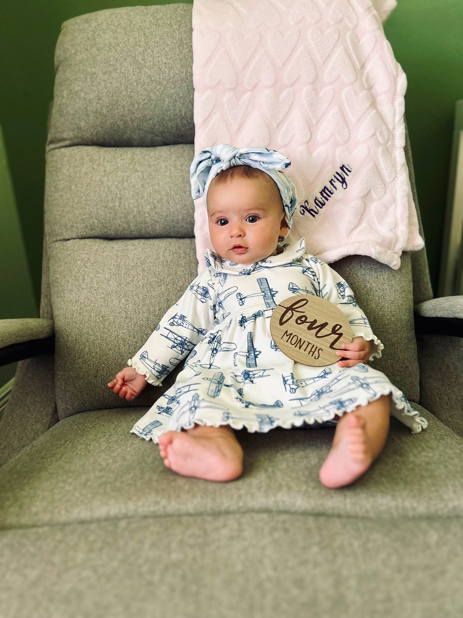 Kamryn is registered to the contest to win money with this photo: baby, baby_toddler_clothing, bedding, cheek, child, comfort, couch, eye, fashion_accessory, head, linens, pattern, person, pillow, portrait_photography, sitting, sleeve, t_shirt, throw_pillow, toddler