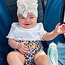 baby, child, smile, white_top, headwrap, paper_towel, checkered_shorts, smiley_faces, baby_shoes, socks, blue_chair, baby_bottle, milk, happy, sitting, infant, cute, indoors, portrait, person