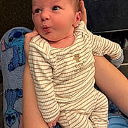 Jacob joined the competition — help win amazing prizes! baby, infant, striped_pajamas, person, arm, hand, blanket, stitch_character, blue_shirt, tattoo, couch, indoor, expression, wide_eyes, puckered_lips, footwear, sock, comfort, holding, seated