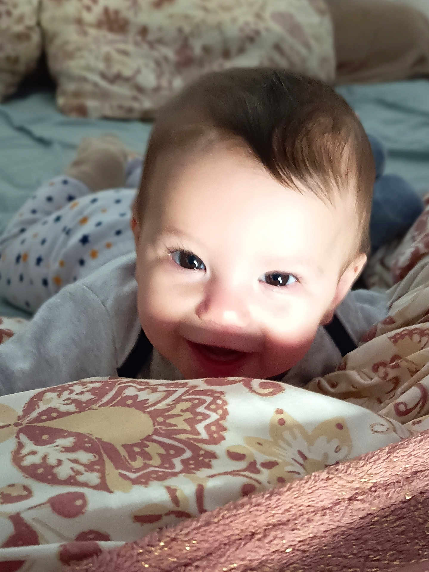 Eyden participe au concours pour gagner de l'argent avec cette photo : baby, smiling, face, child, bed, blanket, pattern, happy, eyes, infant, pajamas, cute, skin, hair, indoors, portrait, person, toddler, playing, cozy