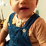 child, toddler, denim_overalls, beige_shirt, indoor, portrait, baby, cute, face, person, young_child, clothing, sitting, curious, soft_focus, skin, head, eyes, mouth, hair