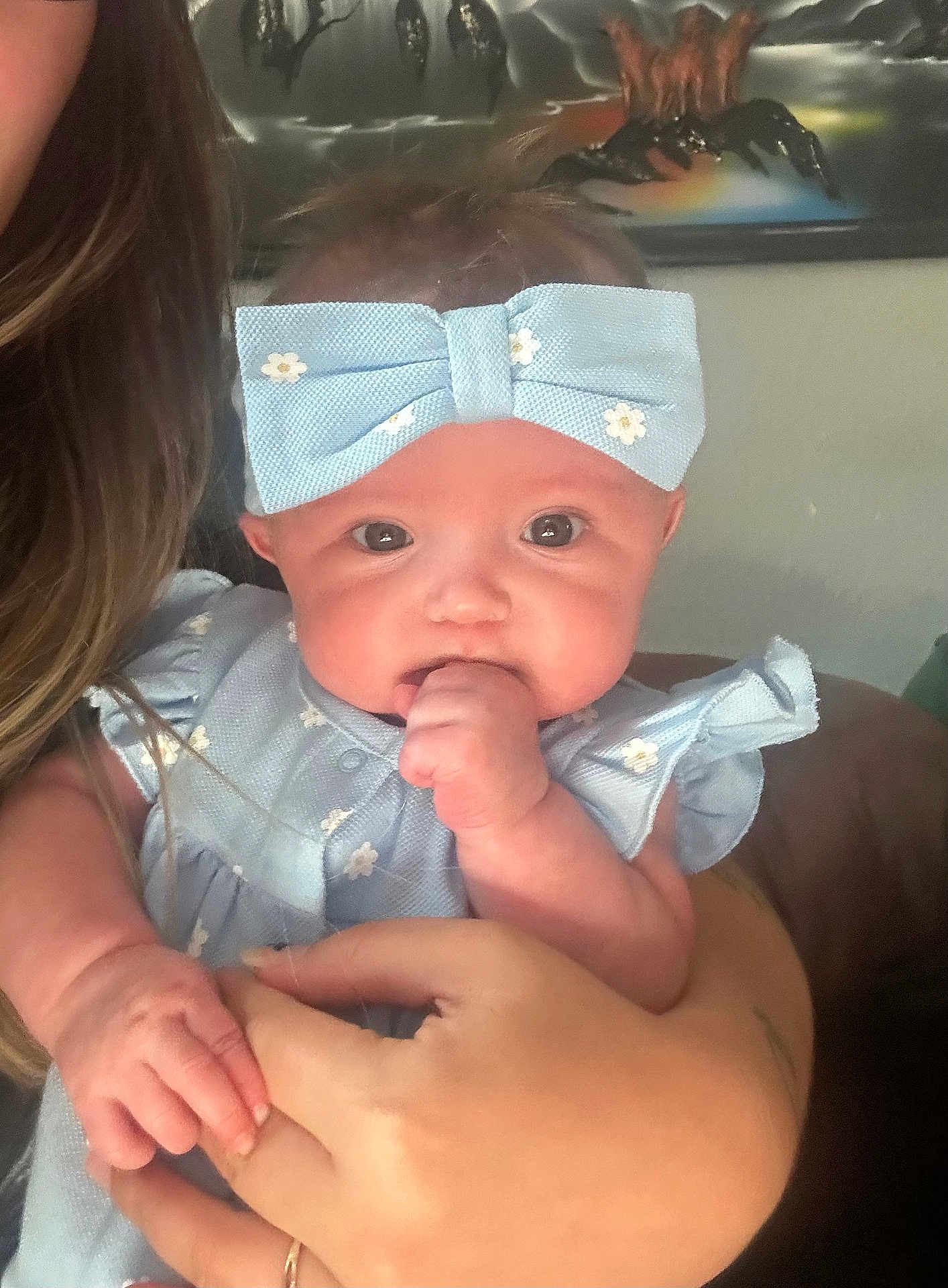 Kayliana joined the competition — help win amazing prizes! baby, child, headband, blue, dress, hand, fist, face, person, indoor, portrait, cute, holding, skin, hair, adult_hand, clothing, wall_art, home, infant
