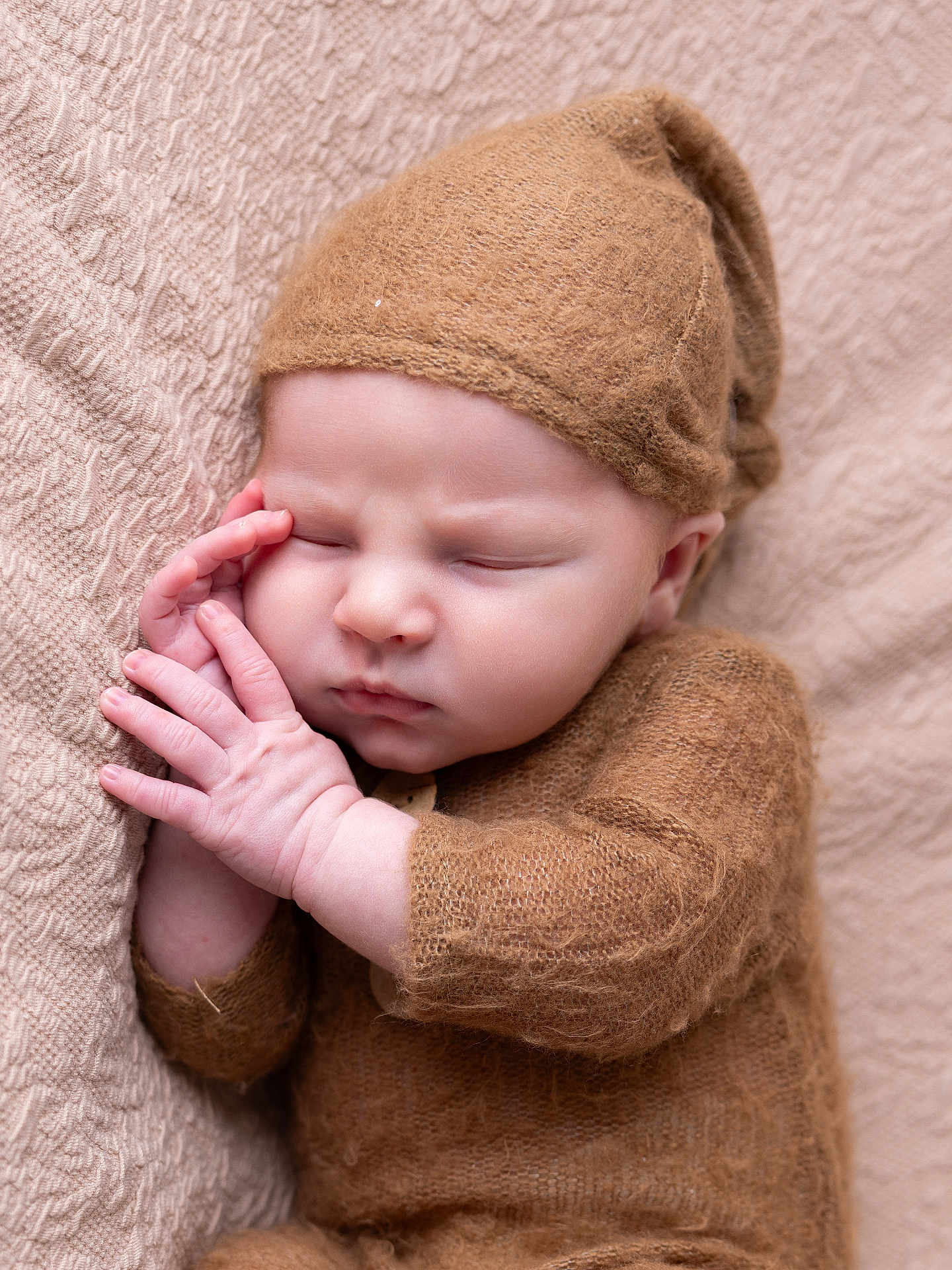 Malo participe au concours pour gagner de l'argent avec cette photo : baby, sleeping, infant, knitted_hat, knitted_outfit, cozy, peaceful, resting, hands, face, blanket, beige, brown, soft_texture, portrait, cute, newborn, child, closeup, toddler