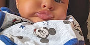 Isma participe au concours pour gagner de l'argent avec cette photo : baby, child, infant, bib, mickey_mouse, pout, face, skin, clothing, necklace, adult, black_top, cute, portrait, closeup, chubby_cheeks, hand, person, indoor, casual