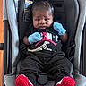 baby, infant, car_seat, clothing, mittens, black_clothes, red_booties, knitted_booties, baby_jogger, seat_belt, person, portrait, indoor, child, cute, young, face, head, sitting, expression