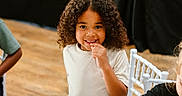 Jakobi joined the competition — help win amazing prizes! bright, casual_clothing, chair, child, curly_hair, cute, friends, happy, indoor, light_skin, people, person, playful, portrait, seated, smiling, table, white_shirt, wooden_floor, young