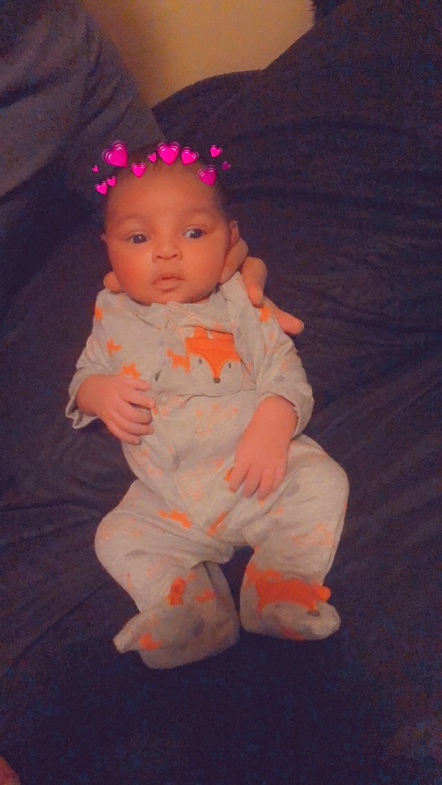 Javon is registered to the contest to win money with this photo: baby, baby_toddler_clothing, cheek, child, comfort, eye, flooring, fun, head, iris, lip, magenta, nose, person, pink, sitting, skin, sleeve, thumb, toddler