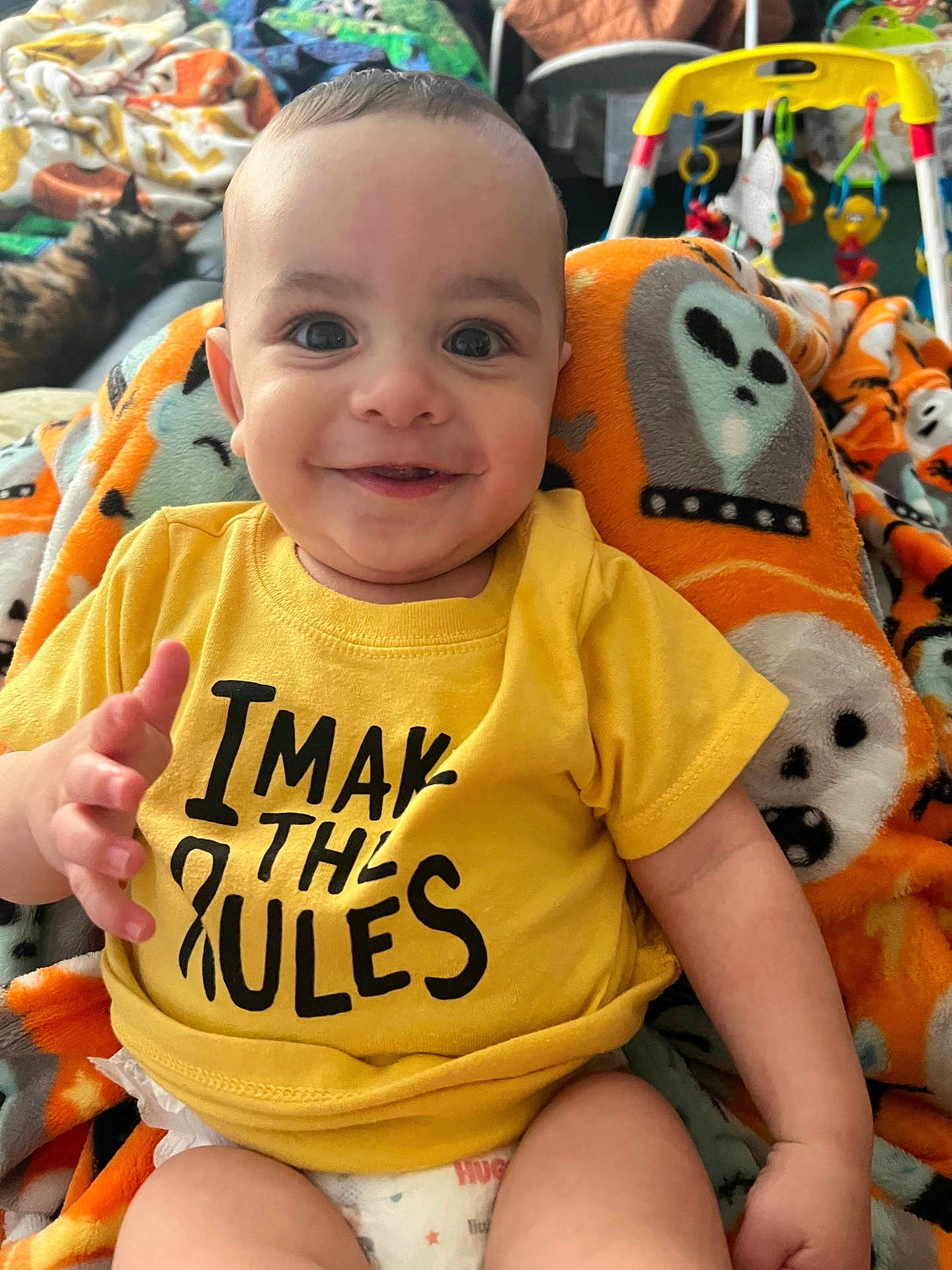 Roman joined the competition — help win amazing prizes! baby, smiling, yellow_shirt, blanket, diaper, face, child, toy, cat, indoor, happy, cute, infant, sitting, colorful, expression, playful, home, cozy, portrait