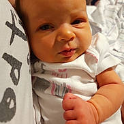 Addisyn is registered to the contest to win money with this photo: baby, infant, closeup, face, hand, clothing, white_outfit, skin, newborn, portrait, expression, resting, fist, person, cute, indoors, soft_lighting, curious, young_child, human