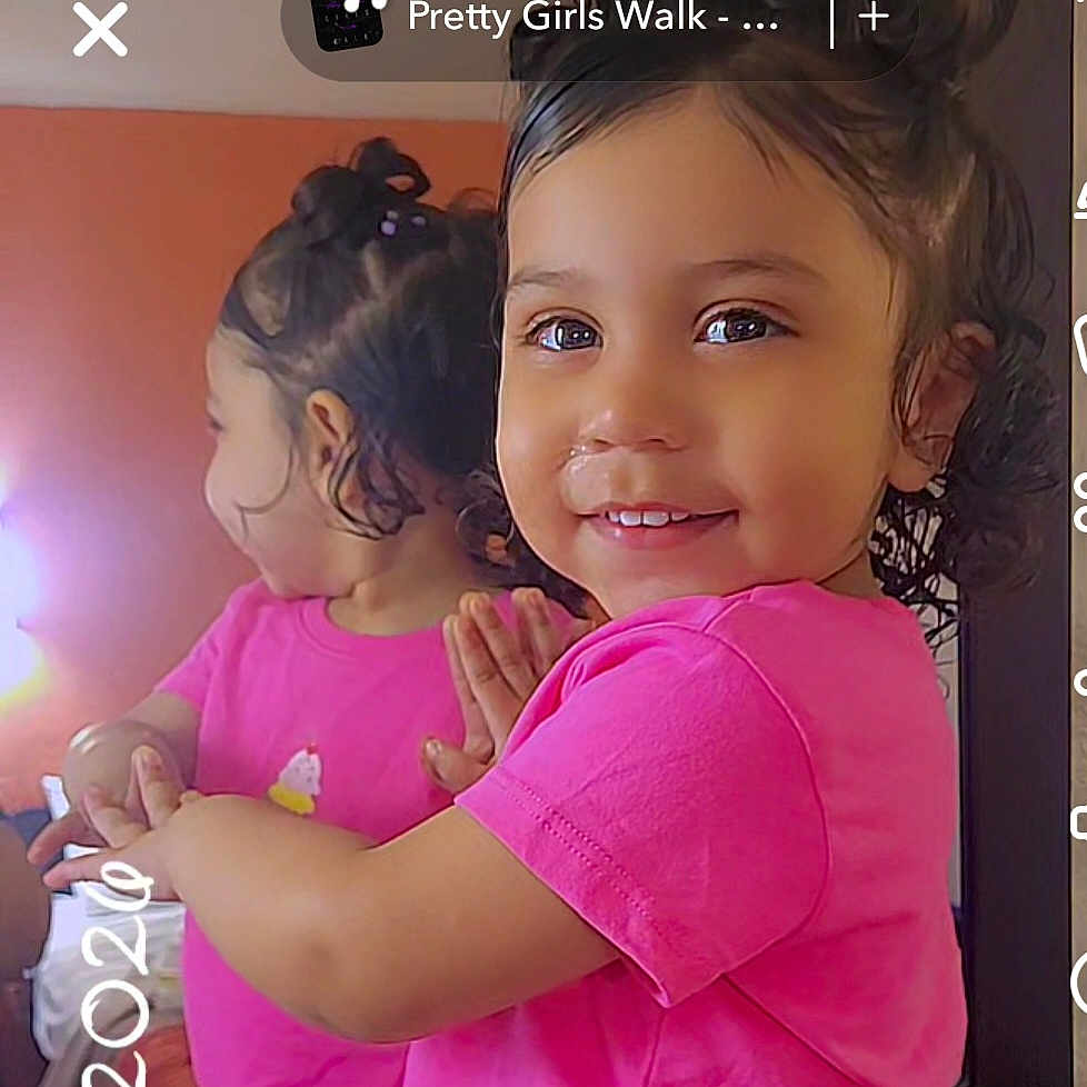 Mellodie-Grace is registered to the contest to win money with this photo: toddler, child, mirror, reflection, pink_shirt, smile, happy, indoors, curly_hair, face, portrait, person, playful, cute, young_child, casual, home, bright_colors, short_sleeve, closeup