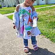 Mellodie-Grace is registered to the contest to win money with this photo: child, girl, smiling, dress, animal_print, jeans, sandals, sidewalk, sunny, outdoor, grass, building, white_building, holding_paper, happy, cute, pose, shadow, daytime, portrait