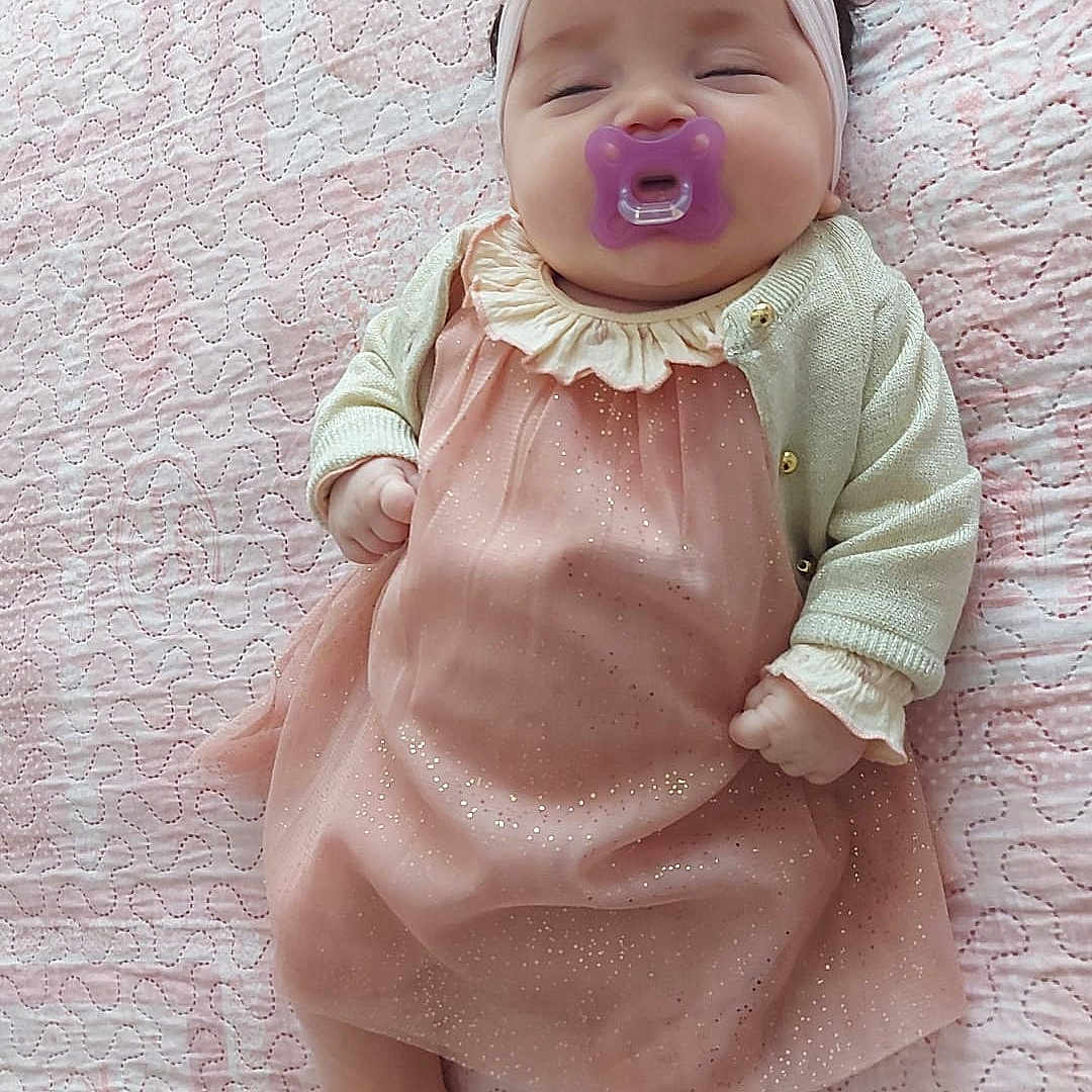 Defne participe au concours pour gagner de l'argent avec cette photo : arm, baby, baby_toddler_clothing, blond, cheek, doll, dress, eye, finger, iris, lip, mammal, one_piece_garment, pink, skin, sleeve, smile, textile, toddler, toy